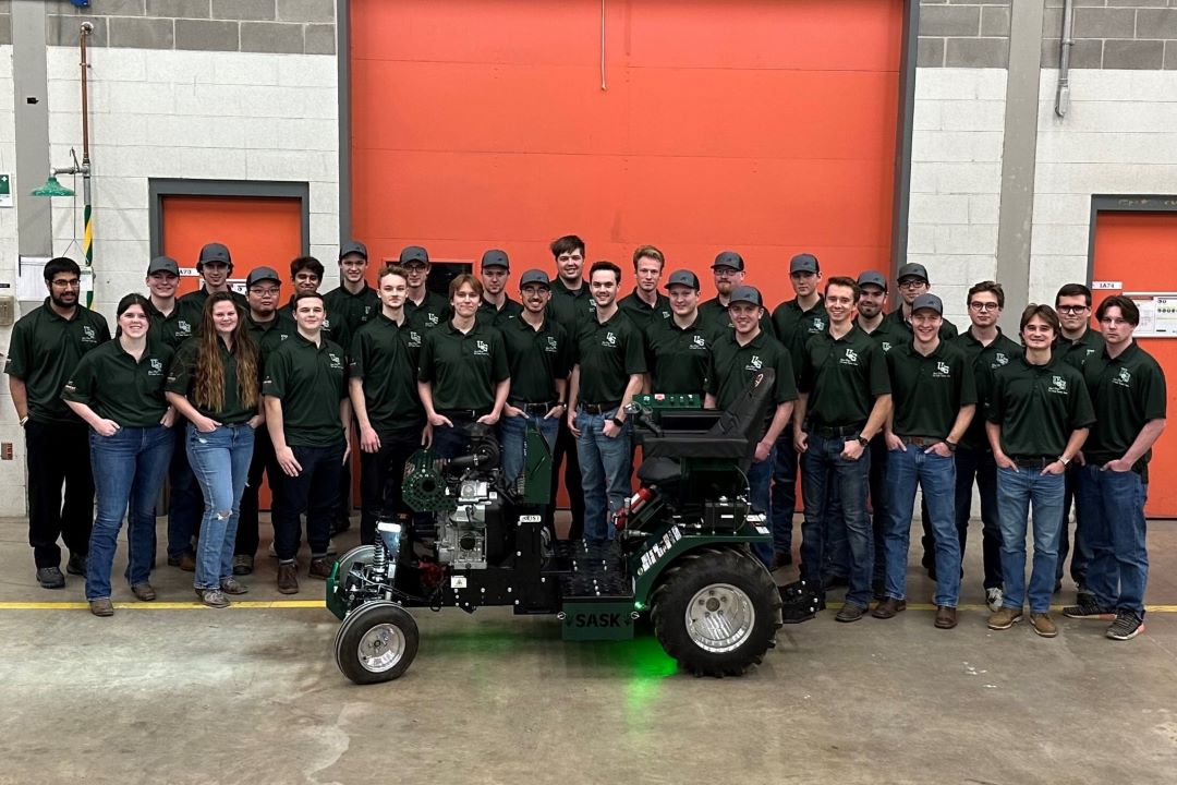 A large group shot of a student group in a workshop area. 